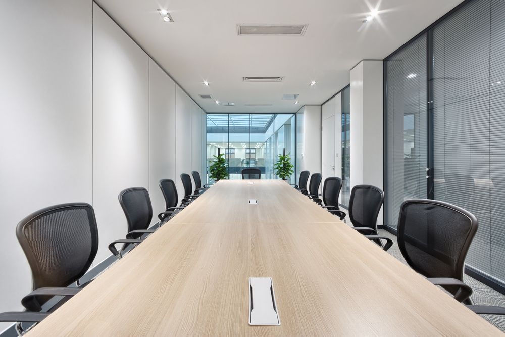 A long wooden conference table with black chairs in a conference room.