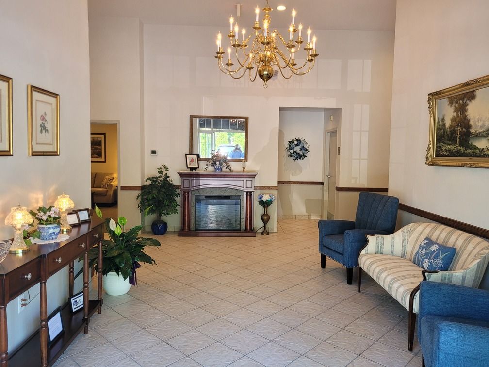 Elegant living room with chandelier, blue armchairs, striped sofa, fireplace, and sideboard with flowers