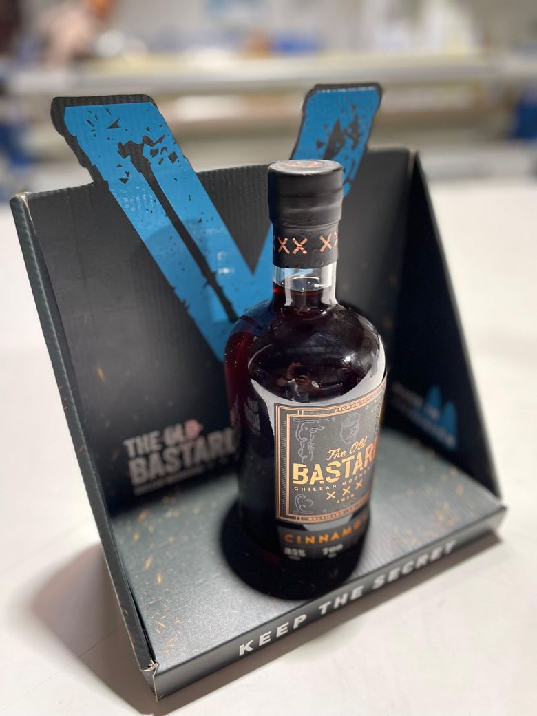 Botella de whisky sobre un soporte negro con un gran fondo azul en forma de "V".