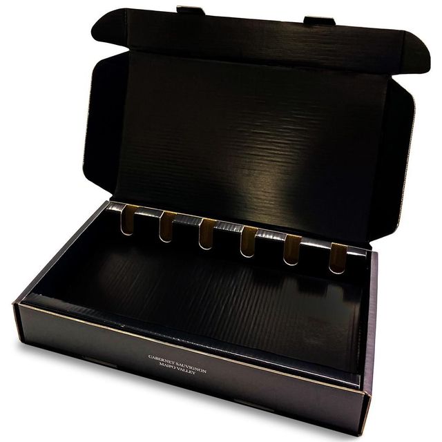 Caja de regalo negra abierta con tapa abatible y una hilera de pestañas doradas en el interior.