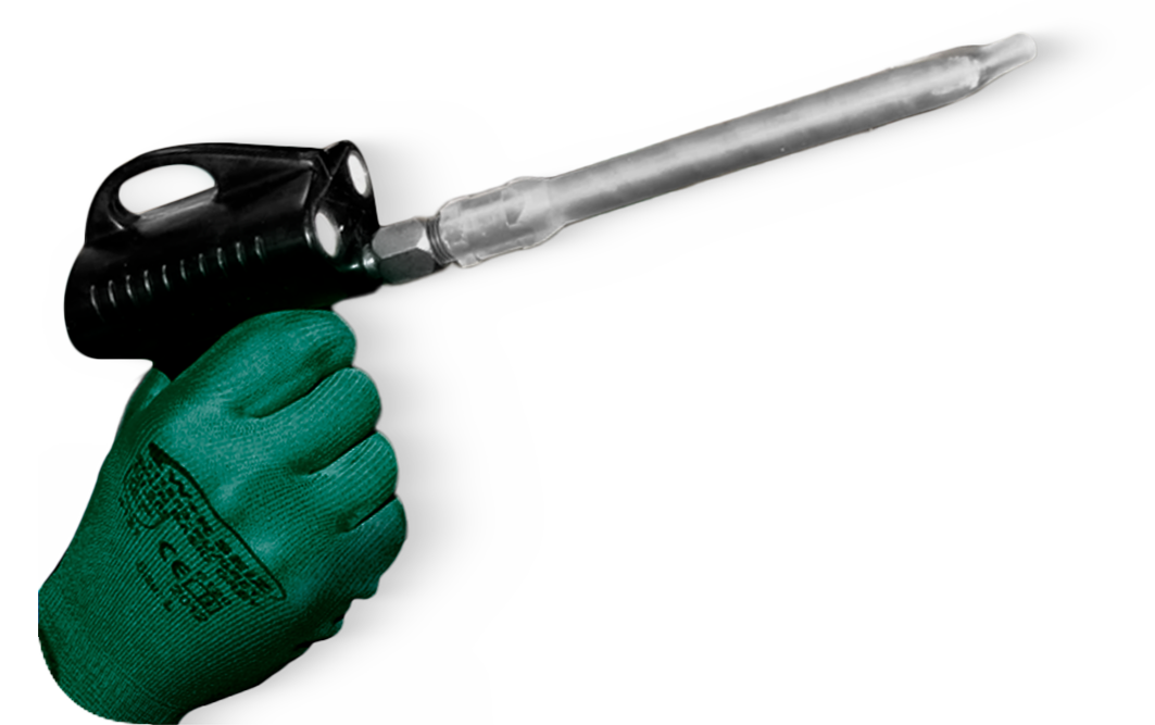 Mão com luva verde segurando uma pistola de calafetagem com cabo preto e bico longo cinza.
