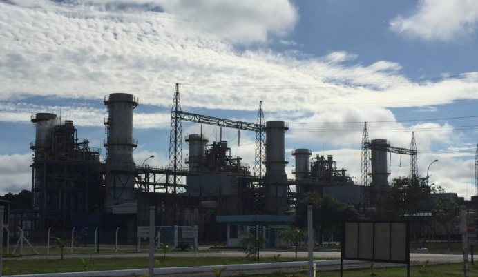 Fábrica com chaminés e torres metálicas sob um céu nublado.