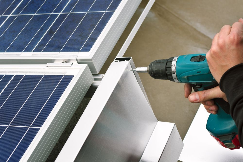 A Person is Working on a Solar Panel With a Drill — B2B Electrical and Solar In Currimundi, QLD A Person is Working on a Solar Panel With a Drill — B2B Electrical and Solar In Currimundi, QLD