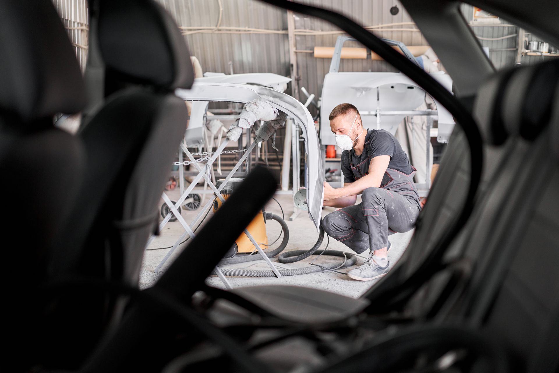 Man working on a bicycle in a workshop, viewed through a car interior.