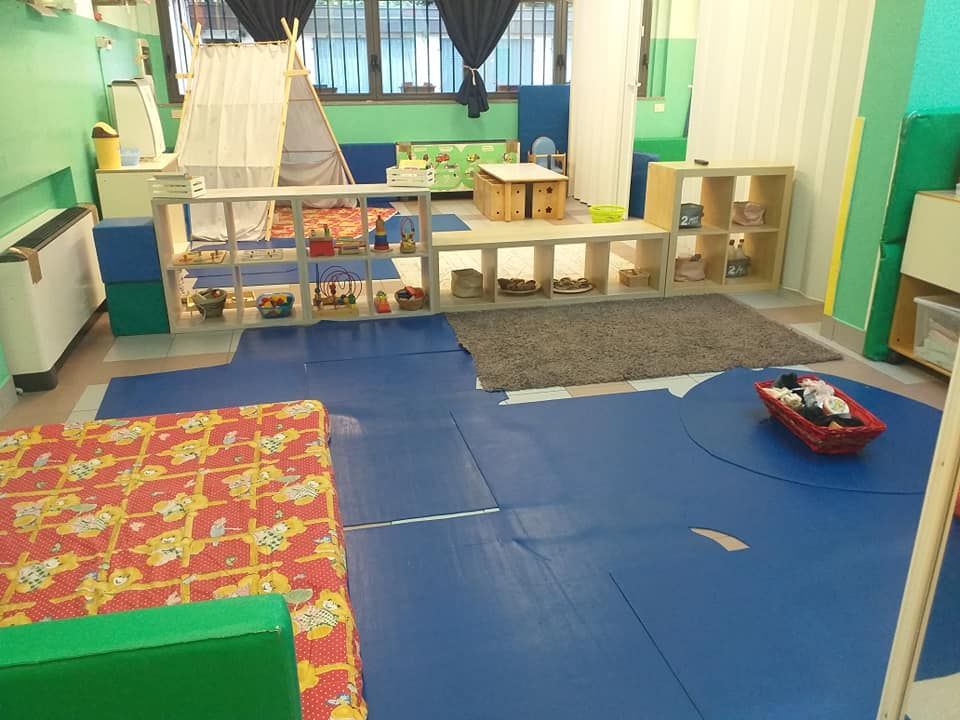 Un'area giochi per bambini con giocattoli sugli scaffali, una tenda indiana e tappeti blu.