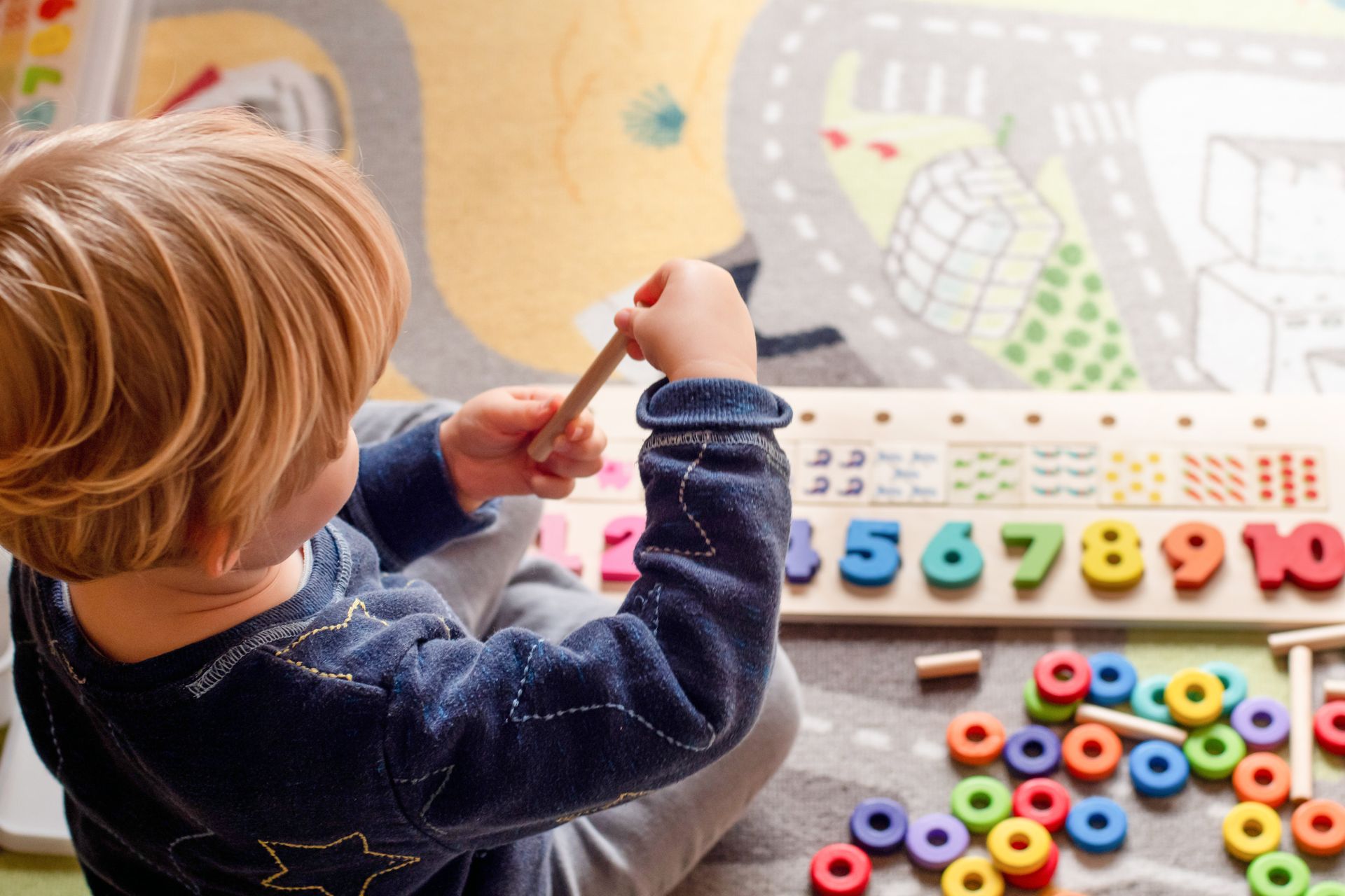 Bambino che gioca con un puzzle di numeri e anelli colorati.