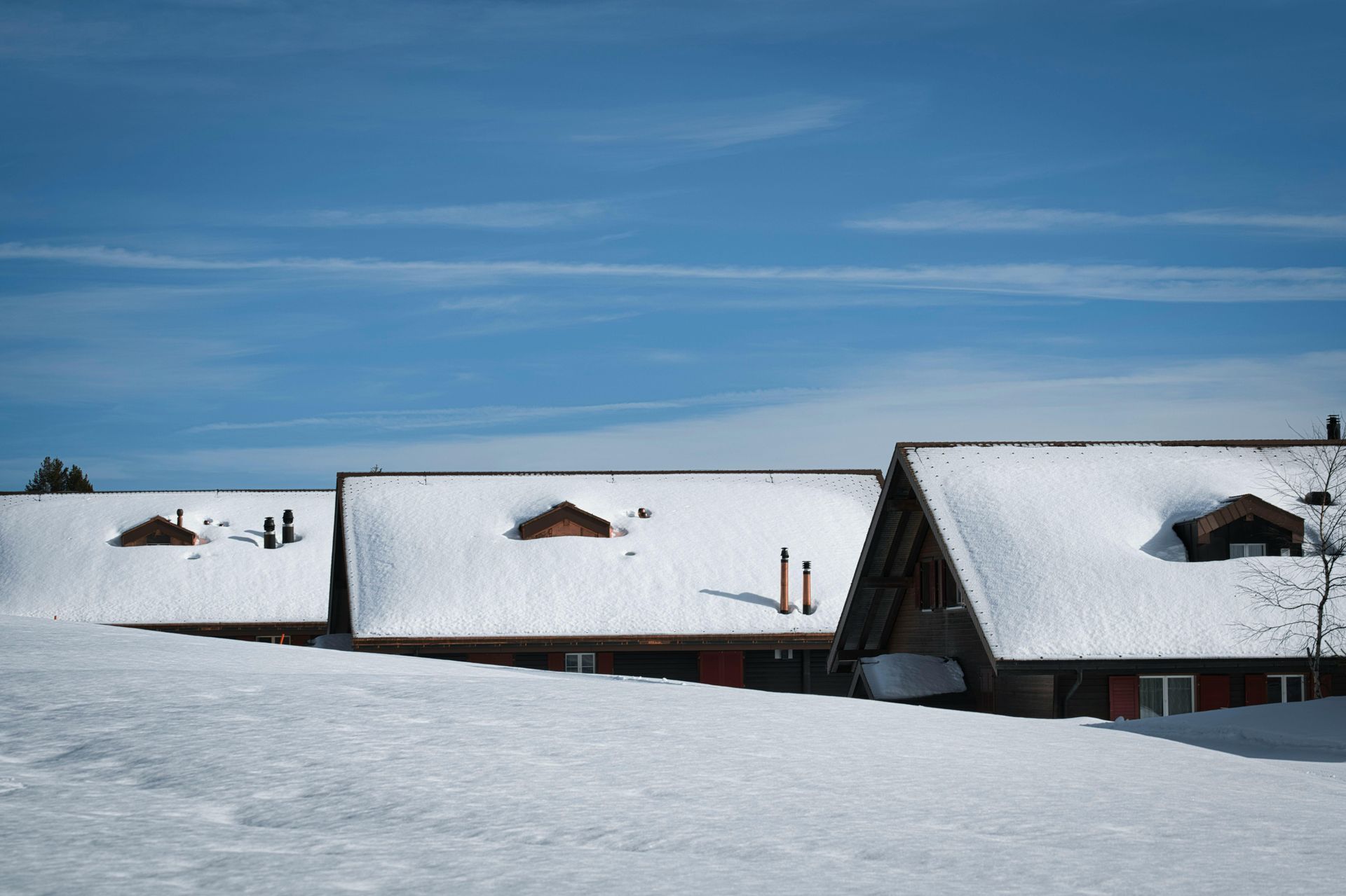 A row of houses covered in snow with a blue sky in the background