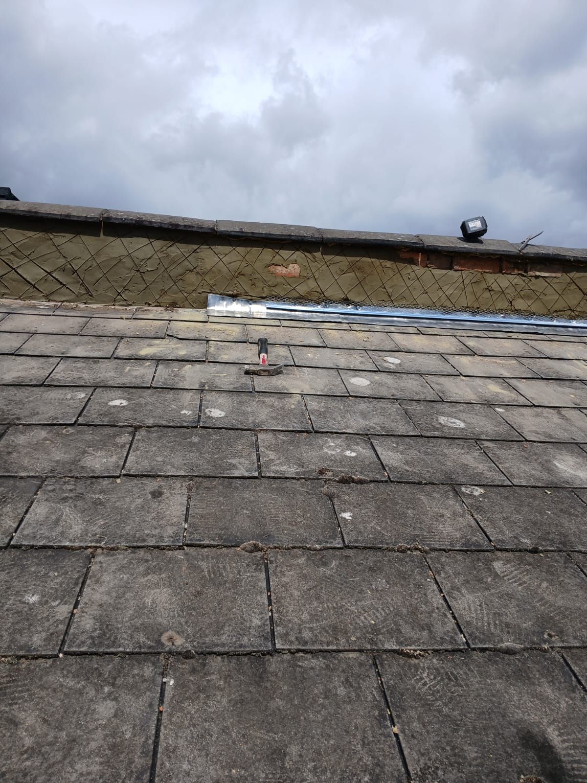 A roof with a lot of shingles on it and a cloudy sky in the background.