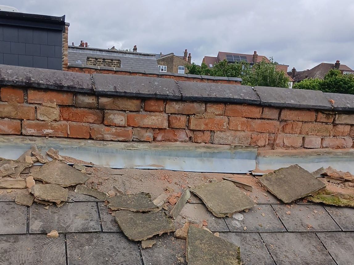 A roof with a lot of rocks on it and a brick wall in the background.