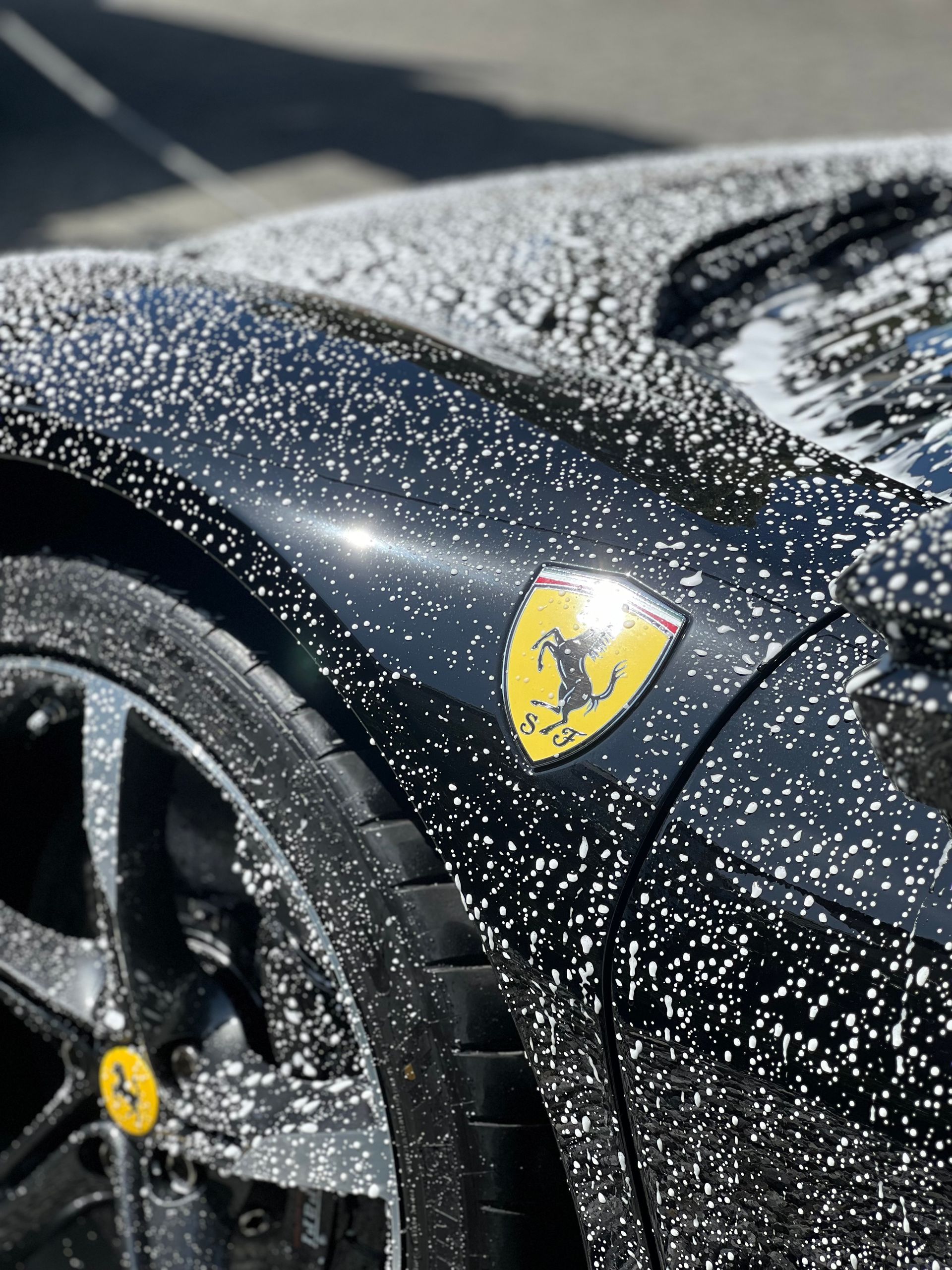 A black ferrari is covered in foam and soap