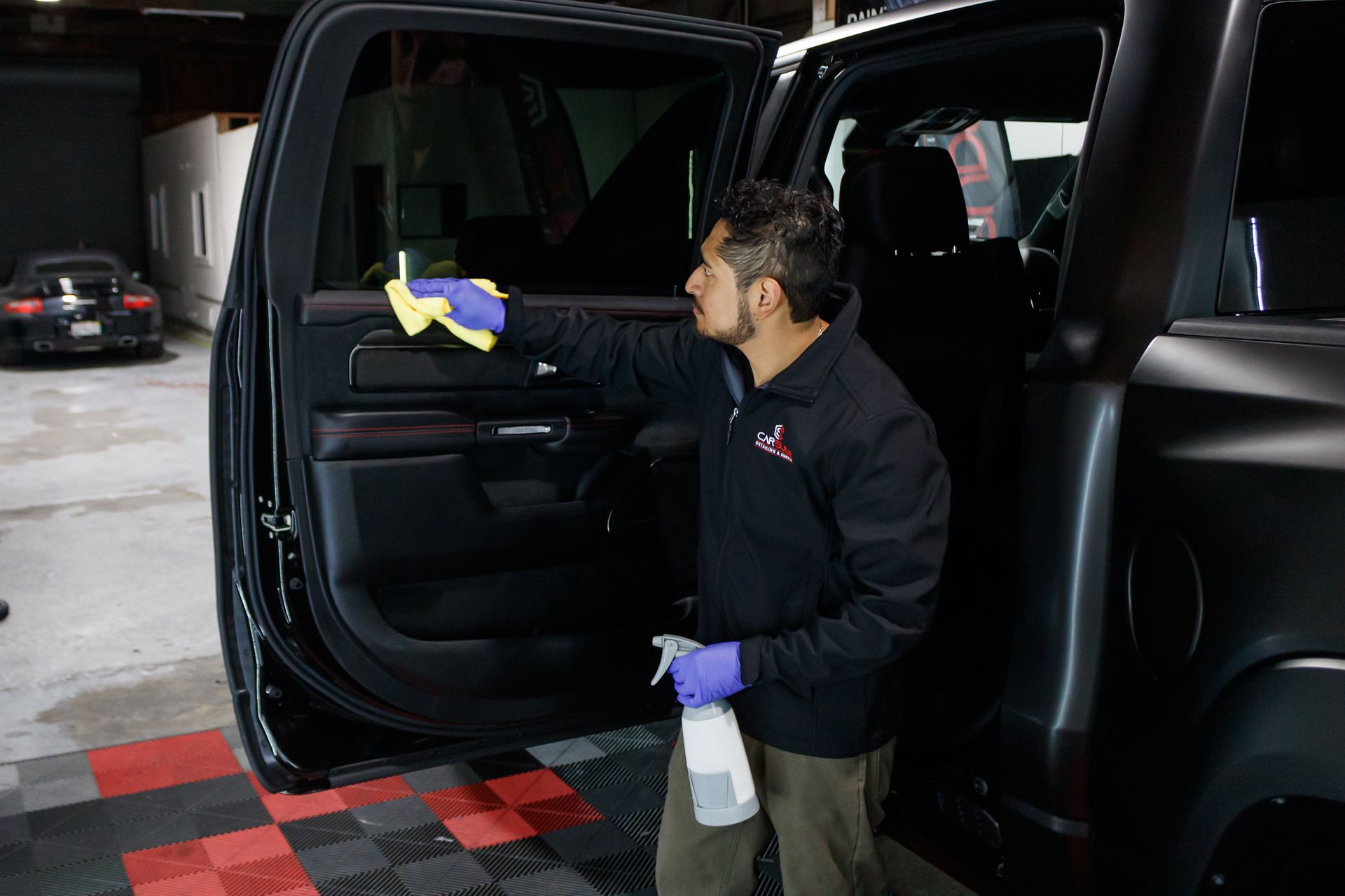 A man is cleaning the door of a black truck.
