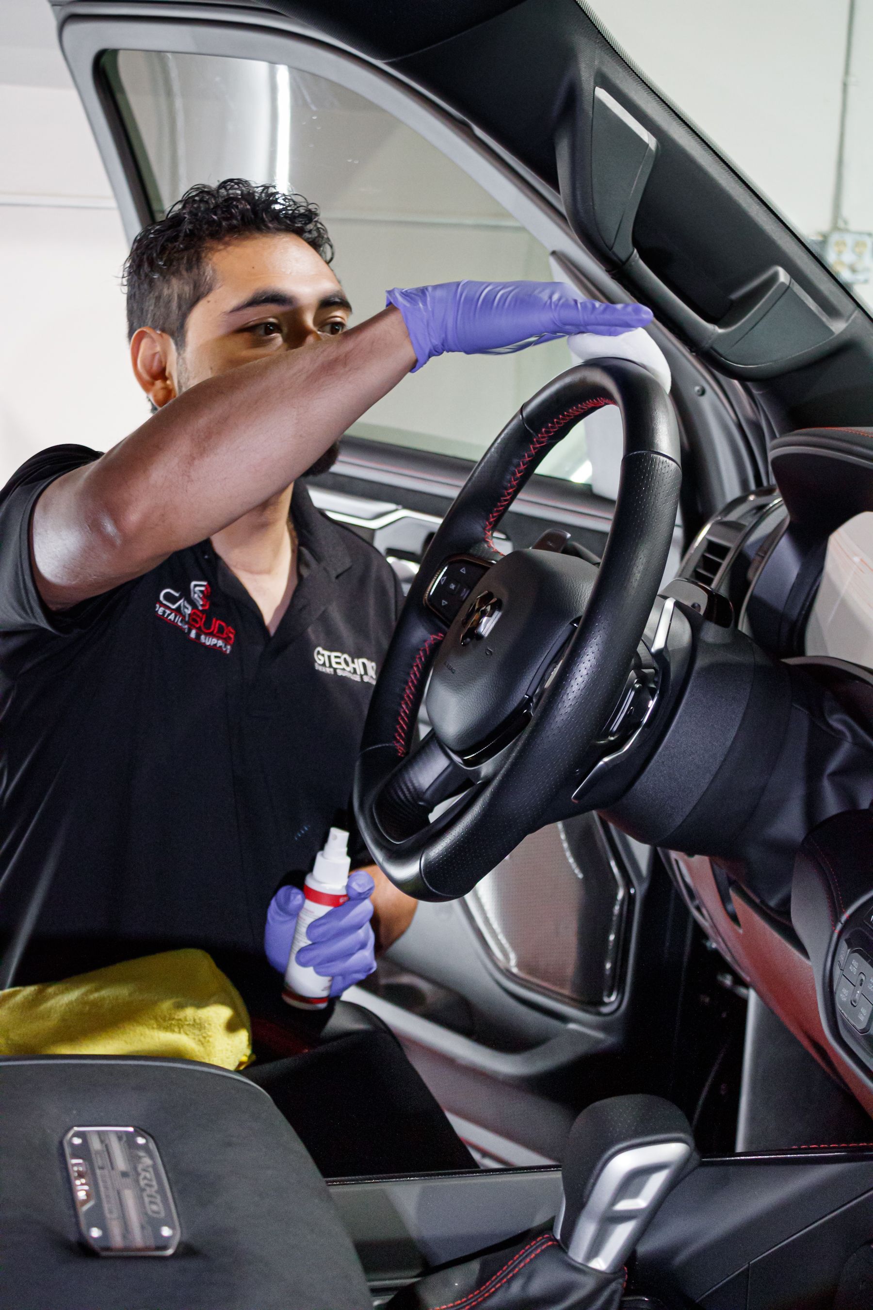 A man is cleaning the steering wheel of a car.