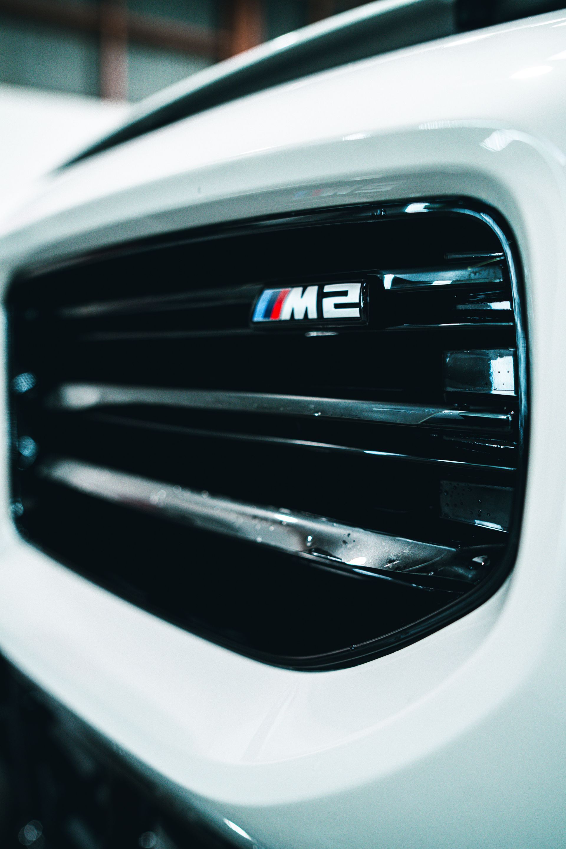 A close up of the front grille of a white bmw m2.