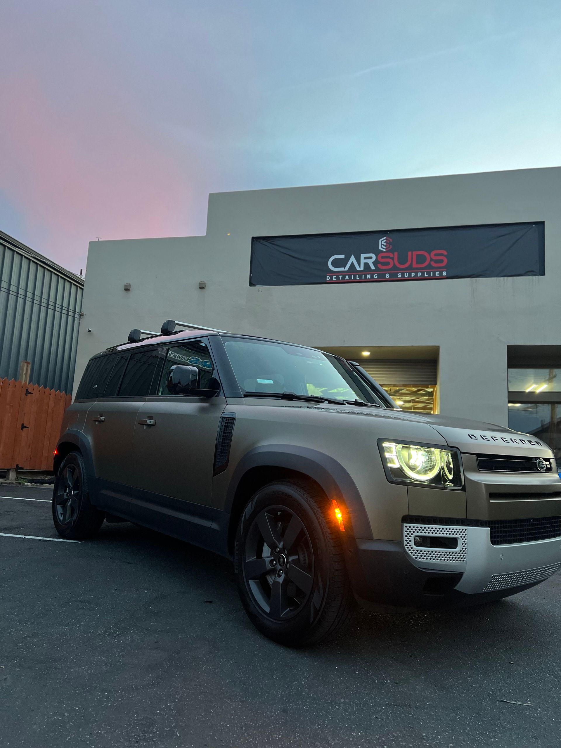 A car is parked in front of a building that says car audio.