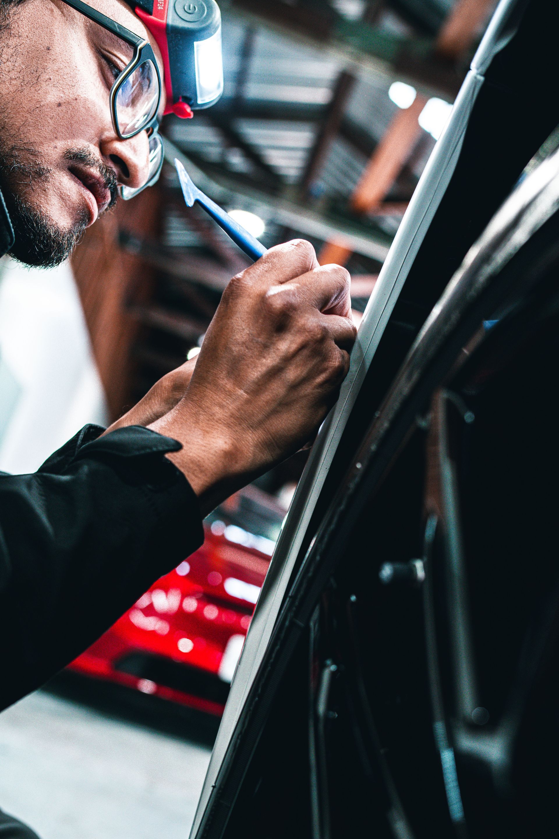A man wearing glasses is working on a car in a garage.