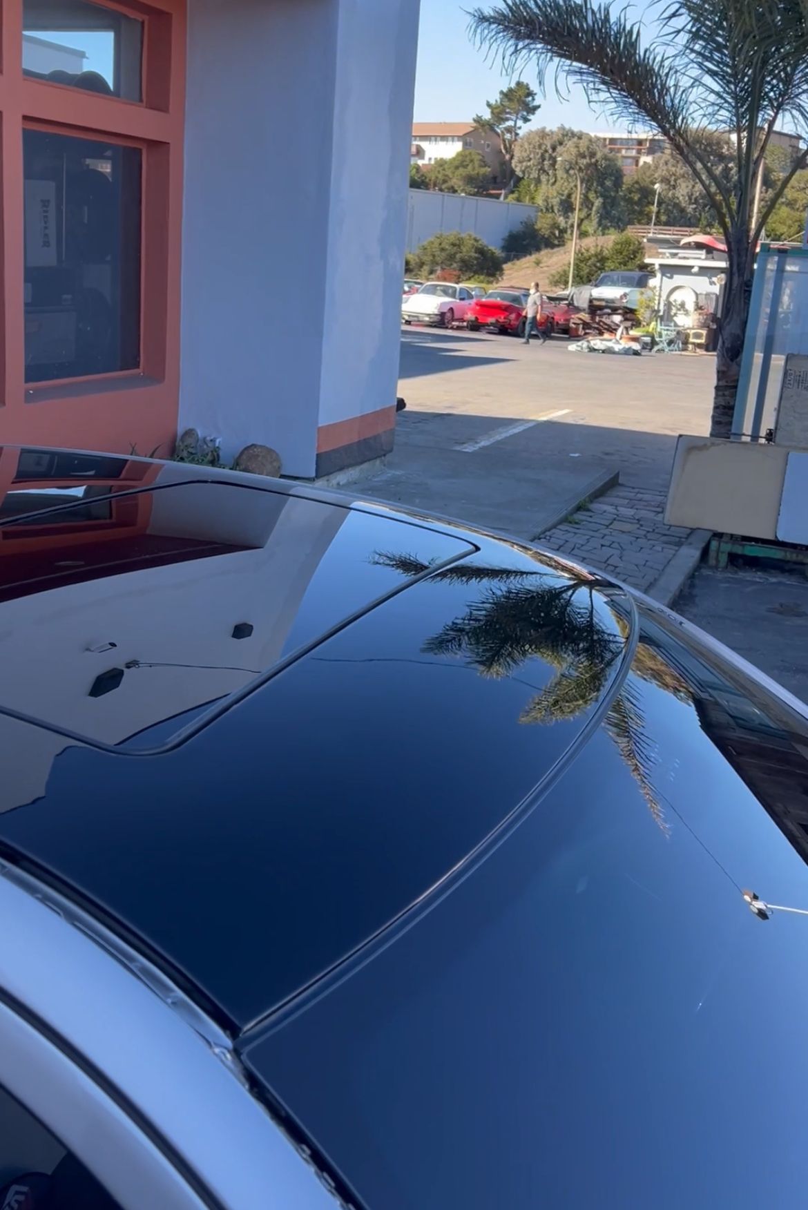 A car with a black roof is parked in front of a building.