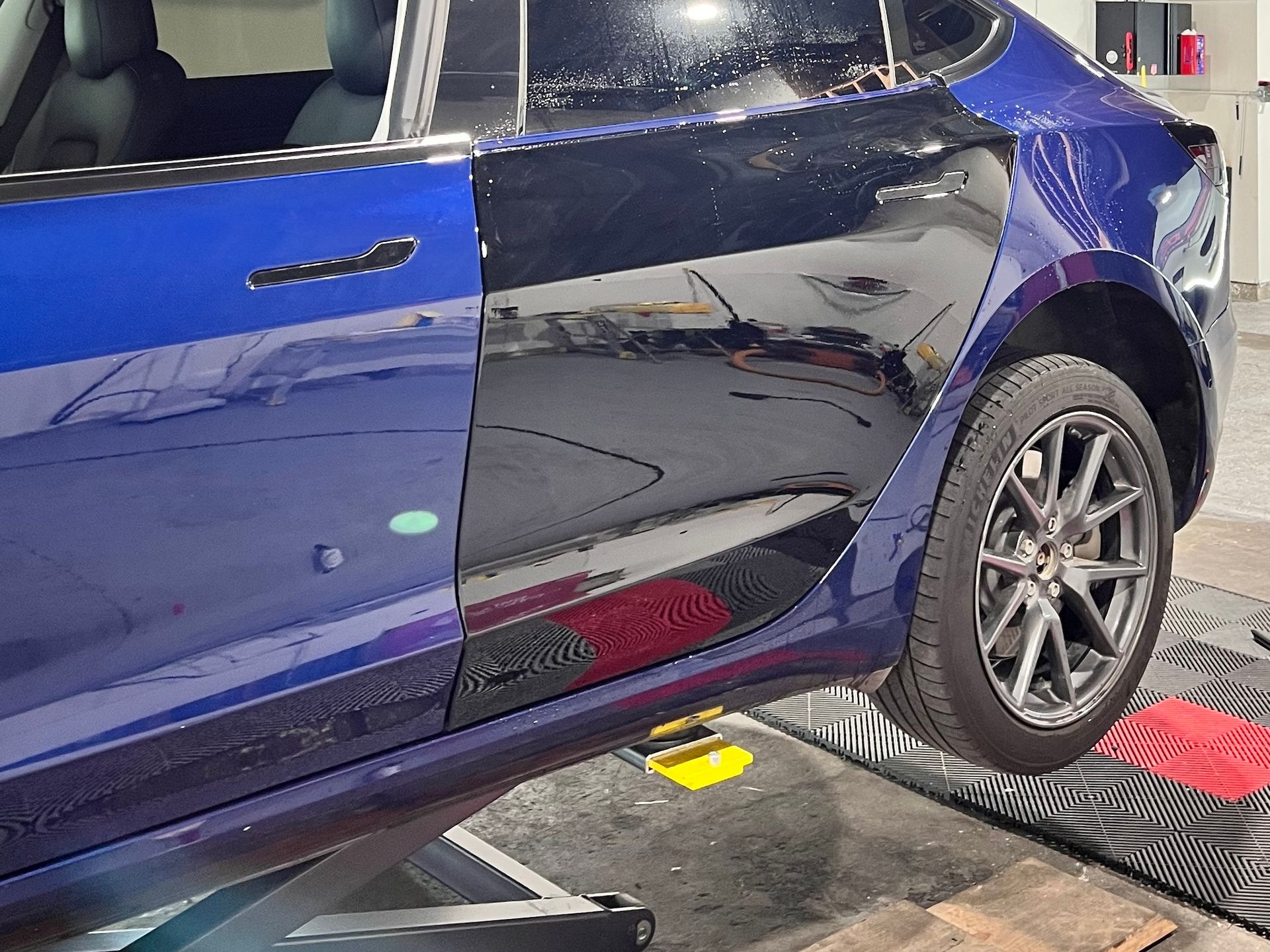 A blue car is sitting on a lift in a garage.