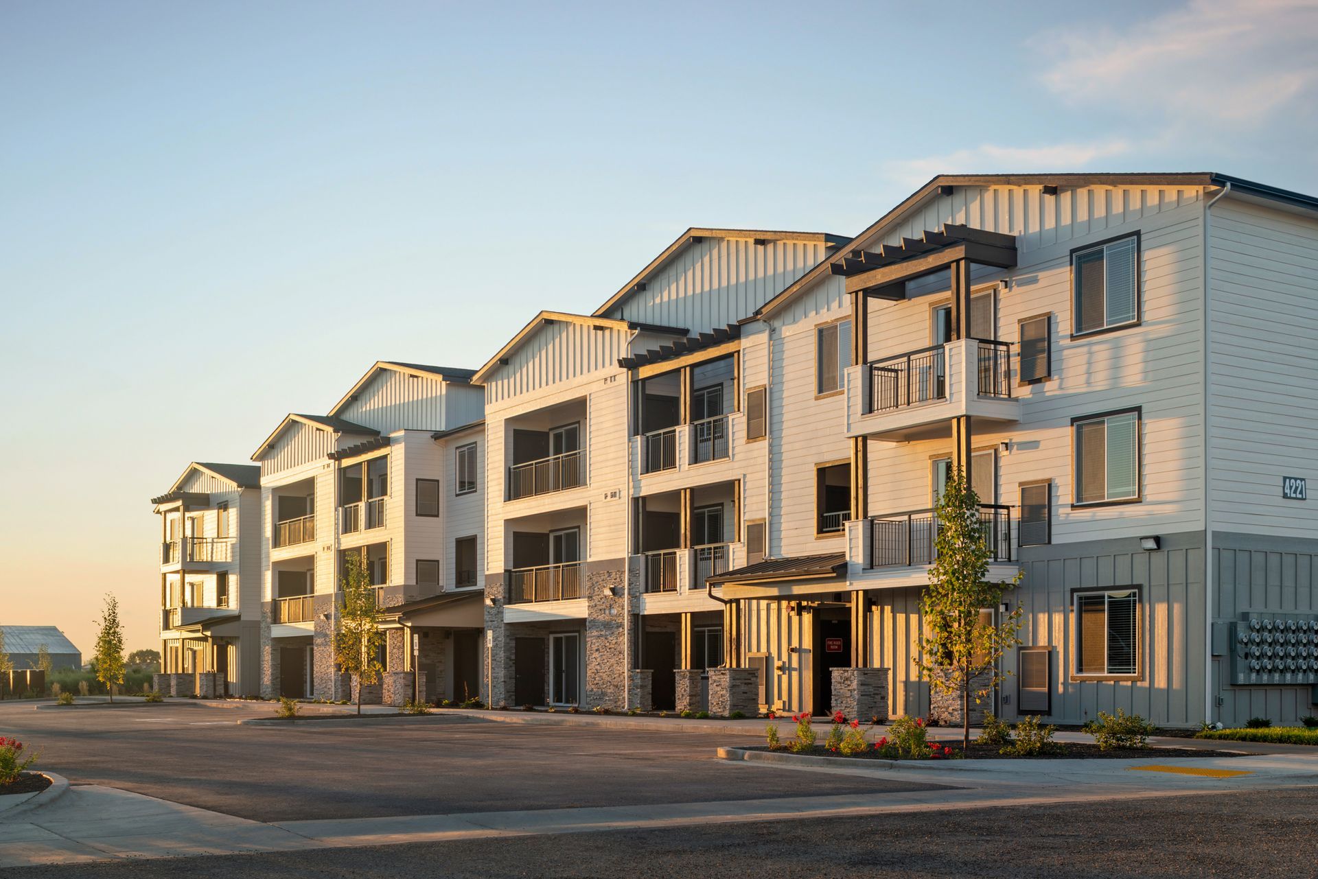 Modern apartment buildings with balconies at sunset along a quiet street