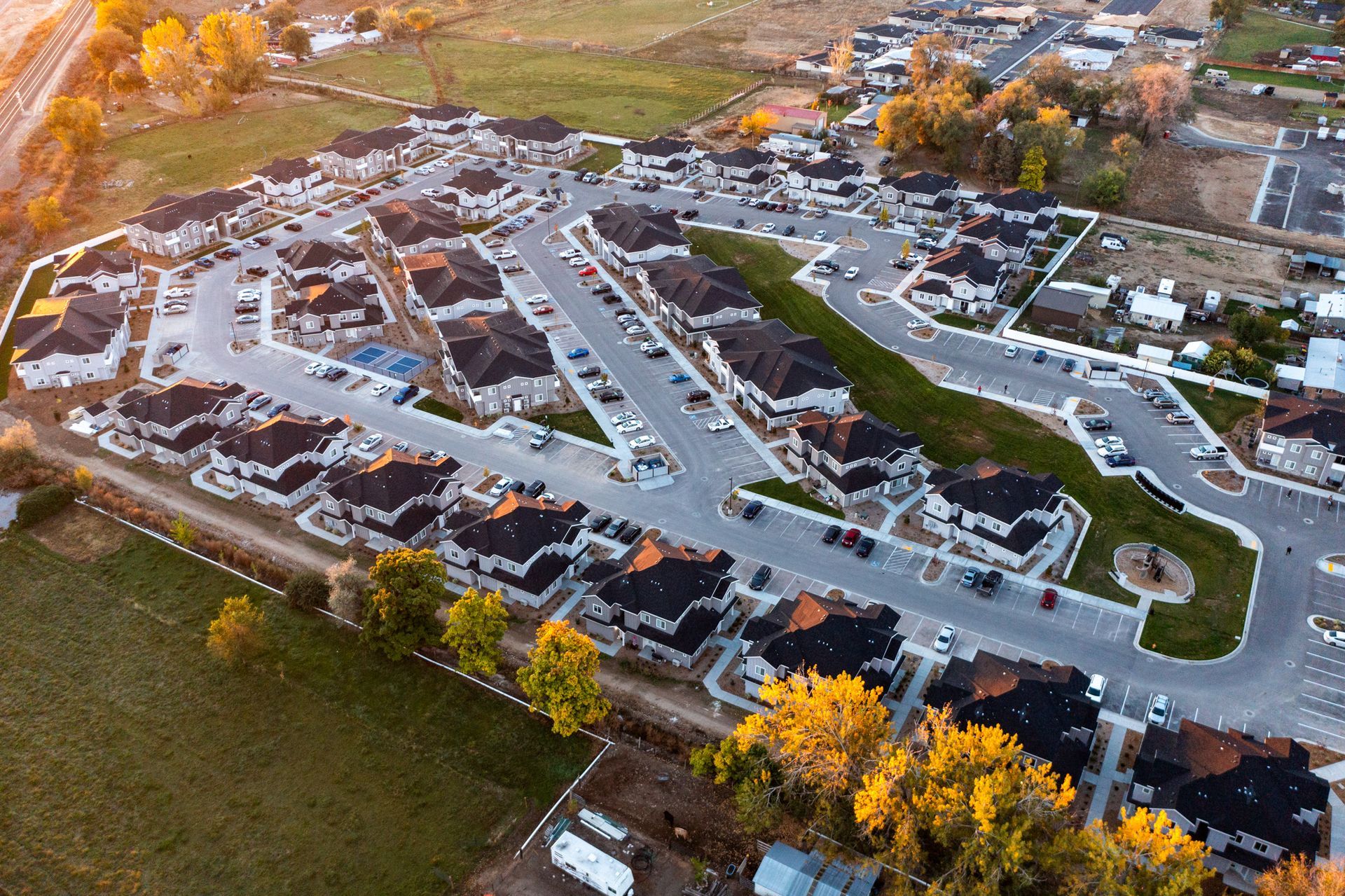 Aerial view of a suburban neighborhood with houses, streets, and autumn trees.