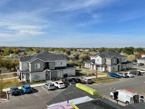 Apartment buildings and parked cars in a residential lot under a blue sky