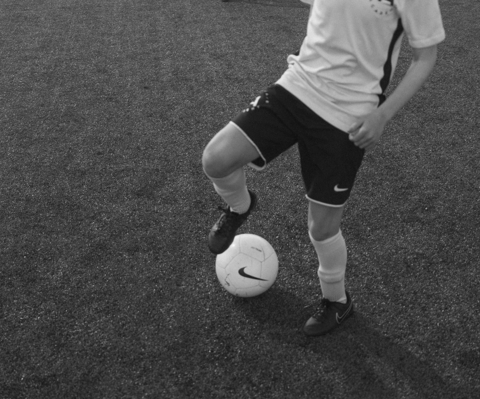 An Advantage Academy player stands on a field with one foot resting on top of a soccer ball