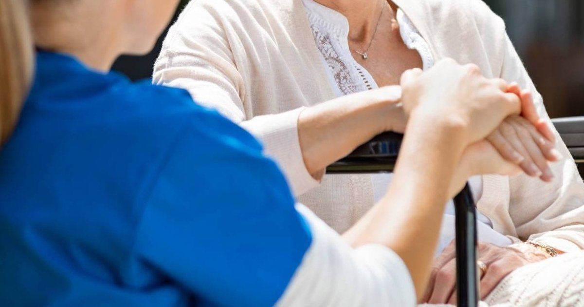 nurse holding elder patient's hand