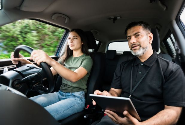 A man is teaching a woman how to drive a car.