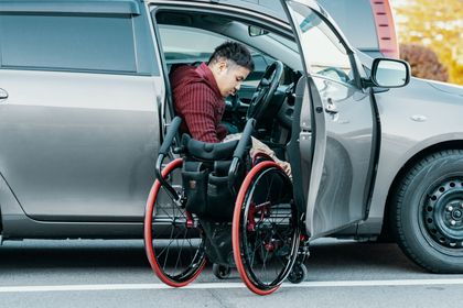 A man in a wheelchair is getting out of a car.