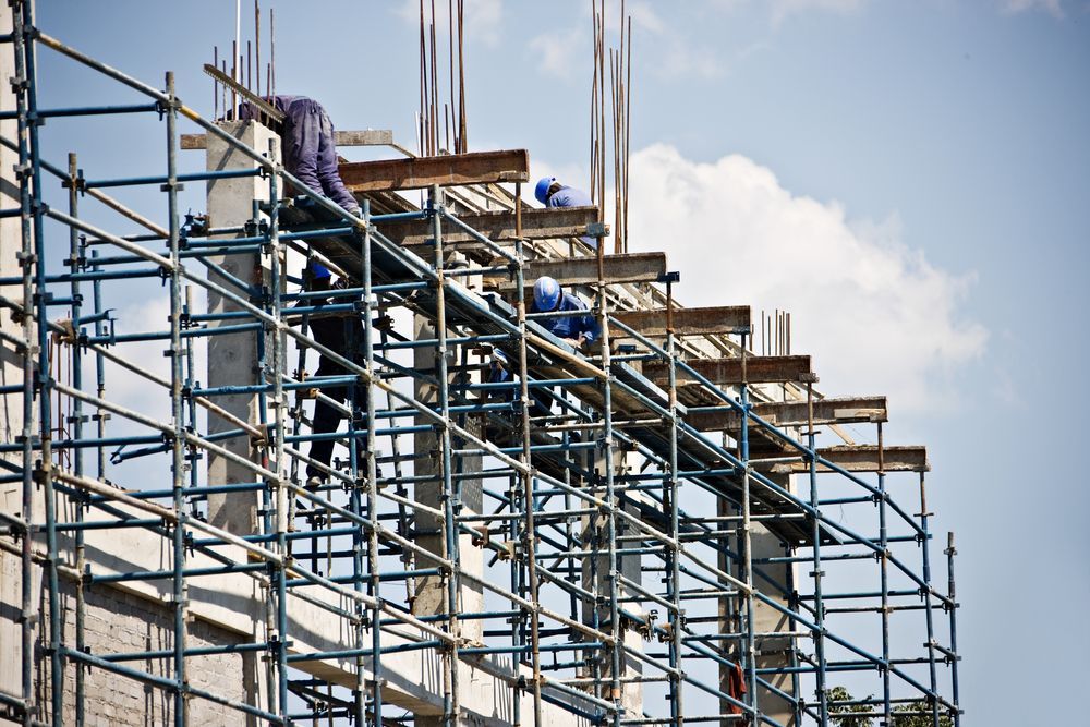 A Group of Construction Workers Are Working on a Building With Scaffolding — NRS Scaffolding Pty Ltd in Yamba, NSW