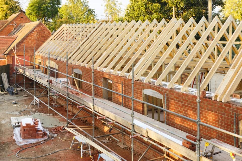 A Brick Building Under Construction With a Wooden Roof and Scaffolding — NRS Scaffolding Pty Ltd in Grafton, NSW