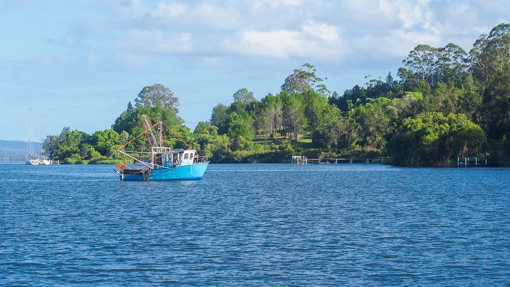 A Blue Boat is Floating on Top of a Large Body of Water — NRS Scaffolding Pty Ltd in Maclean, NSW
