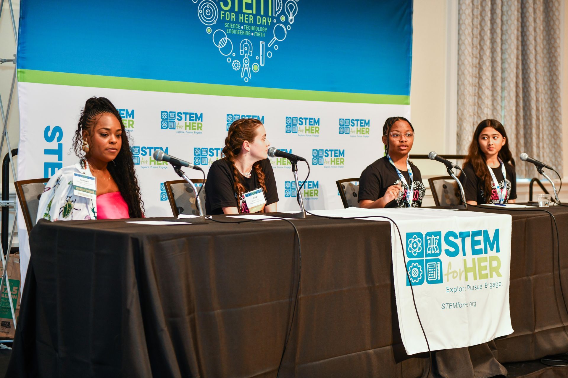 Four panelists seated at a STEM conference table with microphones and a STEM-branded banner.