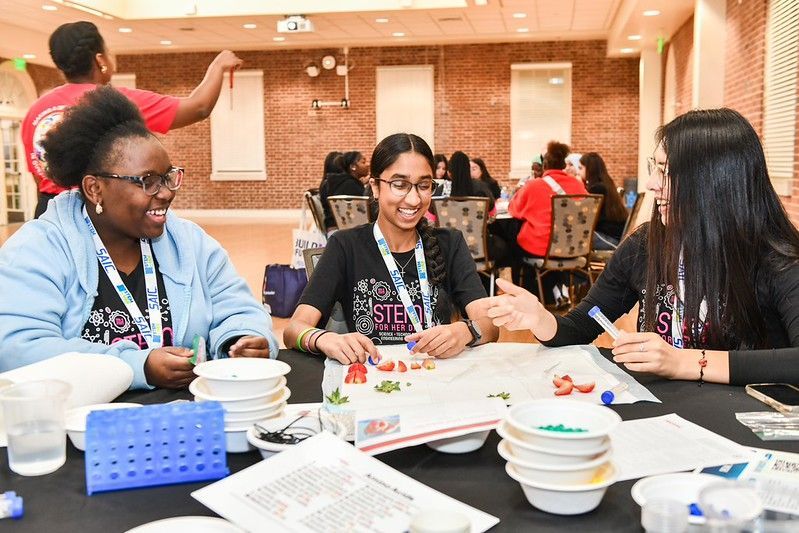 People chatting and eating at a table in a bright cafeteria or conference hall