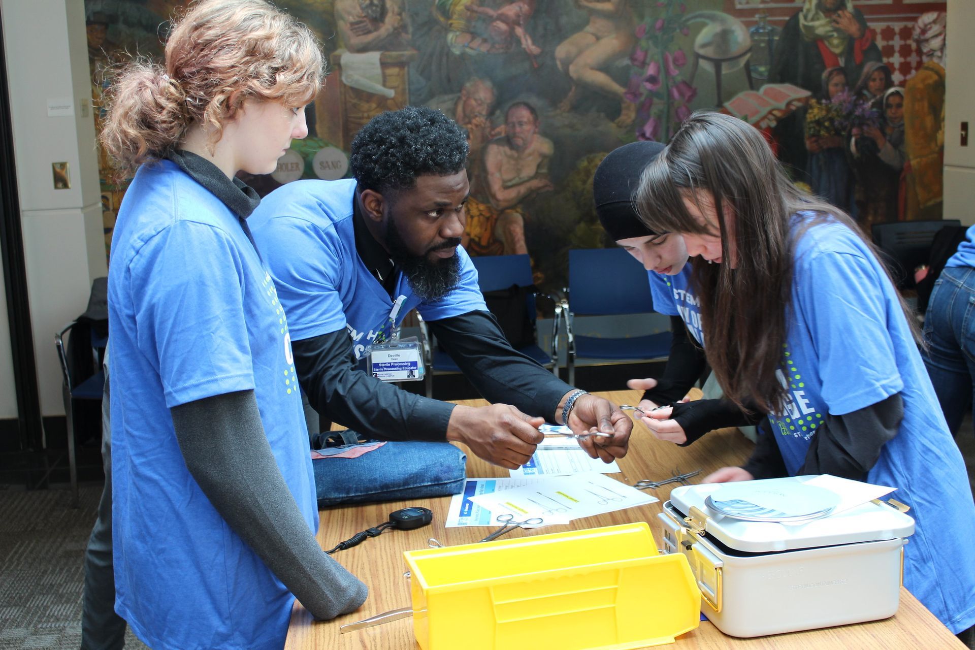 People in blue shirts sorting items at a table during a community event