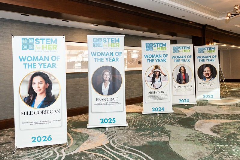 Conference banners for “Woman of the Year” awards displayed in a hotel hallway, labeled 2023–2026.