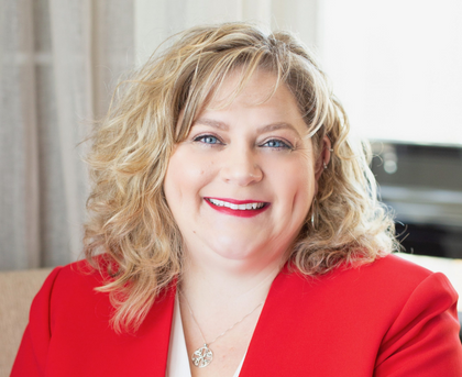 Smiling woman in a red blazer against a light indoor background