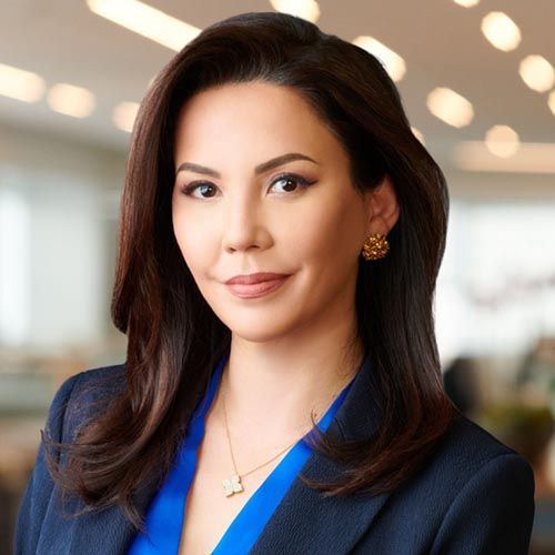 Portrait of a smiling woman in a blue blazer, indoors with a softly blurred office background
