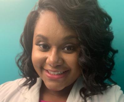 Smiling woman in a white blazer against a teal background