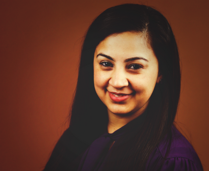 Portrait of a smiling woman with long dark hair against a warm brown background