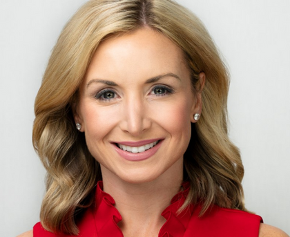 Smiling blonde woman in a red top against a light background