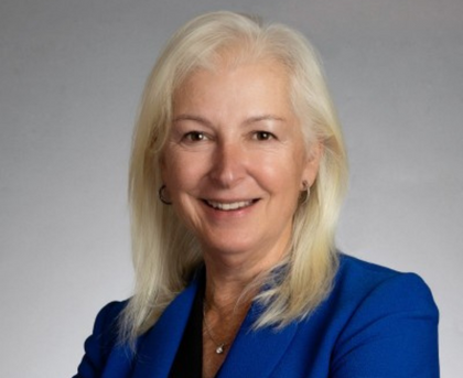 Smiling woman in a blue blazer against a gray background