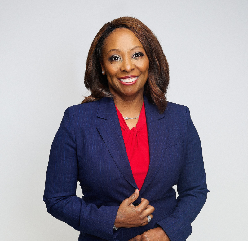 Smiling professional in navy blazer and red blouse against a light background