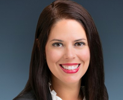 Headshot of a smiling woman with dark hair on a gray background