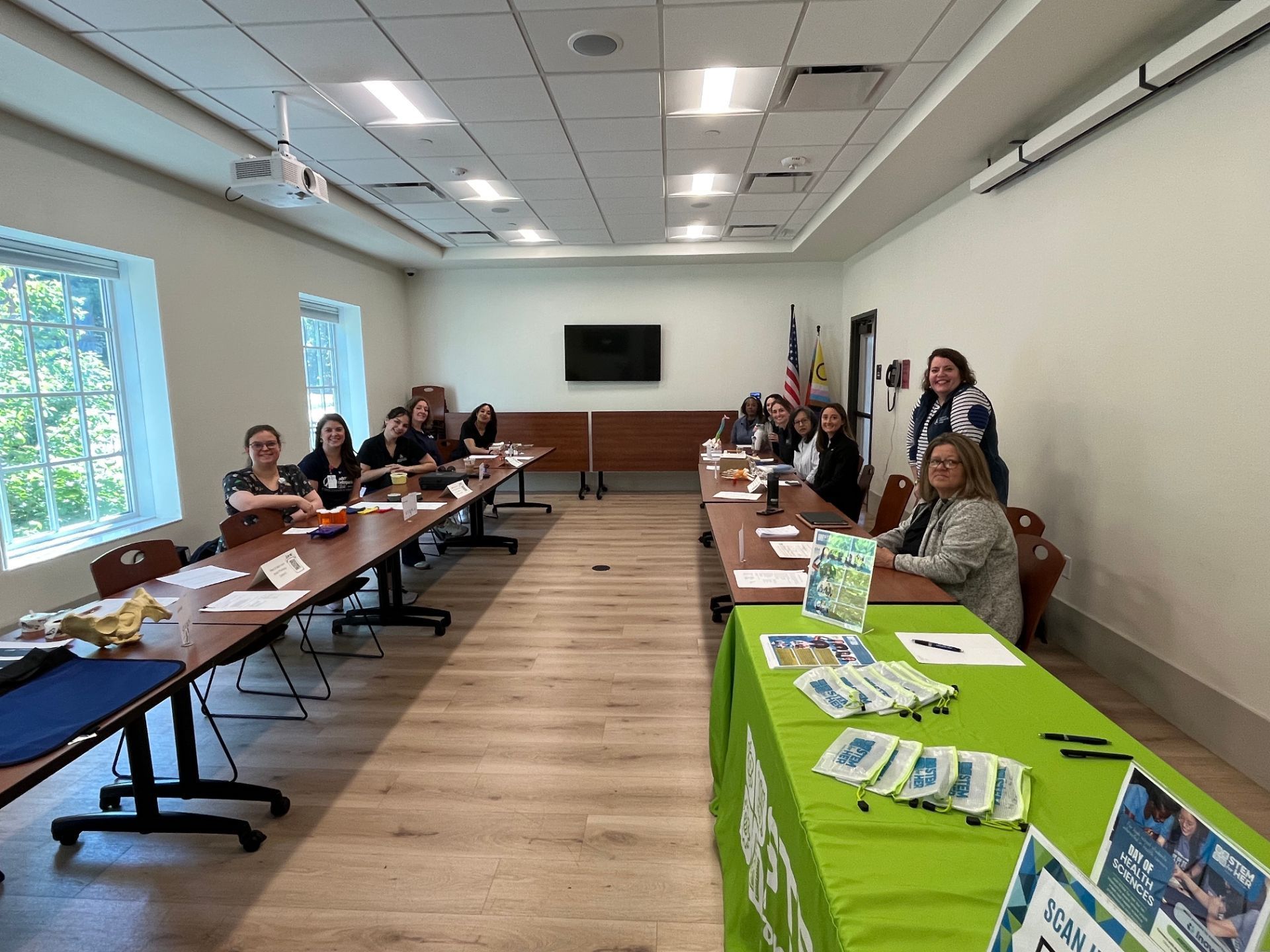Conference room with people seated at tables beside a bright green display table