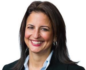 Smiling woman with dark hair in a black blazer against a white background