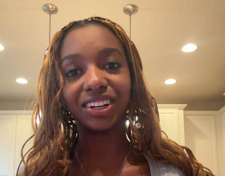 Smiling woman in a kitchen with white cabinets and warm ceiling lights