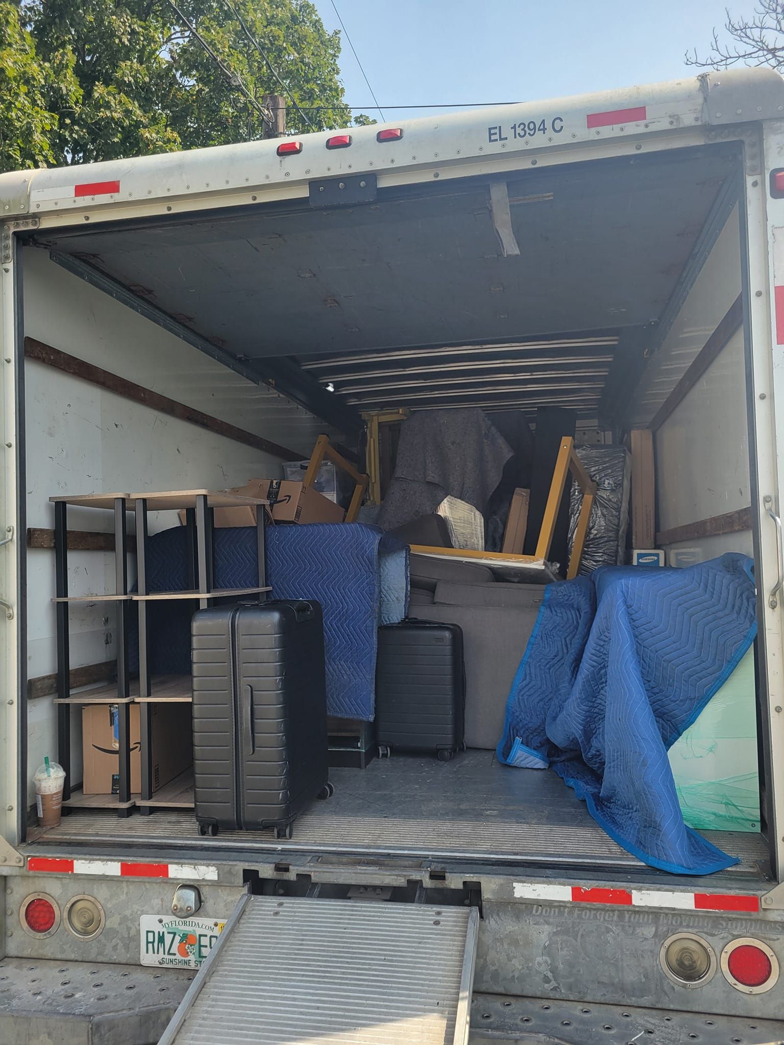 The back of a moving truck filled with furniture and boxes.
