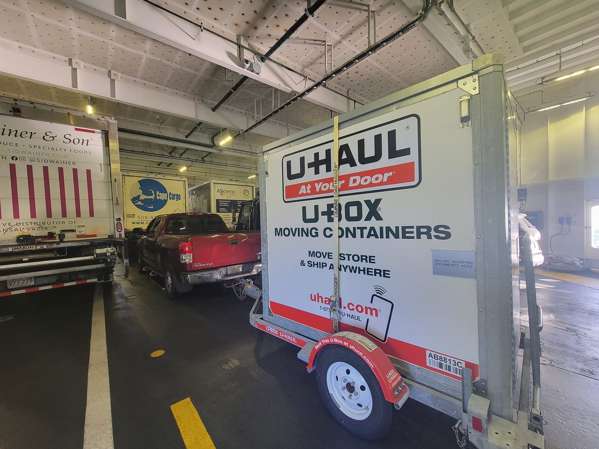 A uhaul trailer is parked in a parking lot next to a truck.