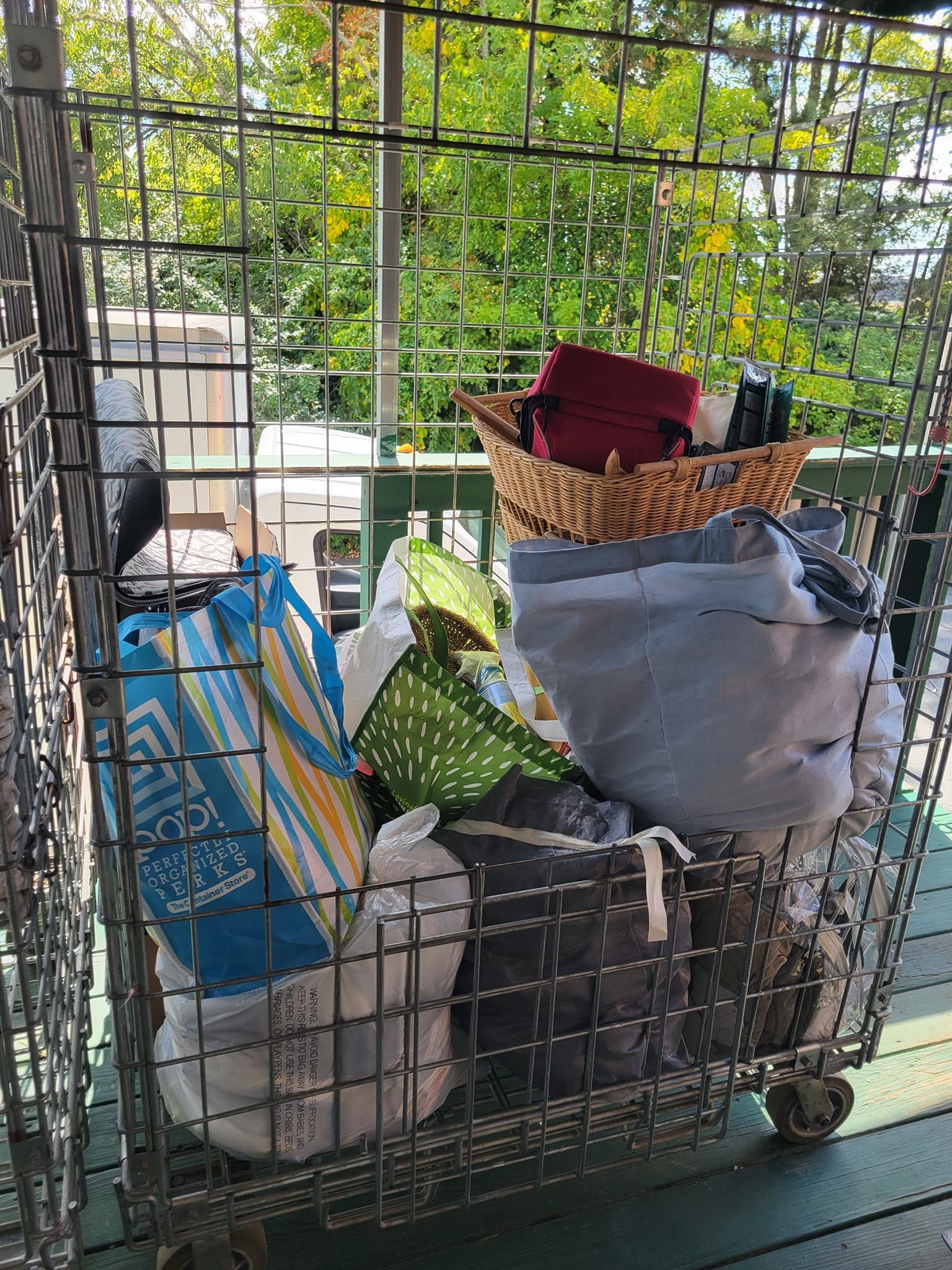 A metal cage filled with bags and clothes on a balcony.