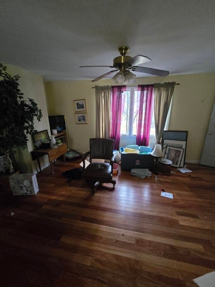 A living room with hardwood floors and a ceiling fan.